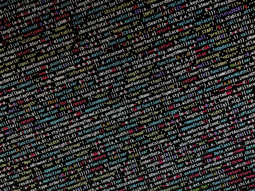 Close-up image of a computer screen displaying a blurred code editor with multicolored programming code, including functions, variables, and commands in various colours such as red, blue, green, yello